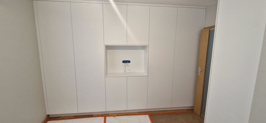 Biała zabudowa z wnęką. Miejsce na panel domofonu